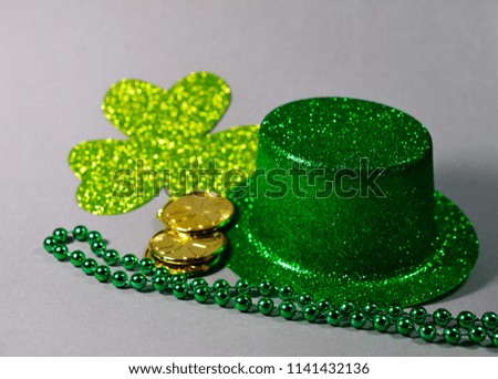 Saint Patrick's Day Top Hat with Shamrock, beads, and coins on gray background
