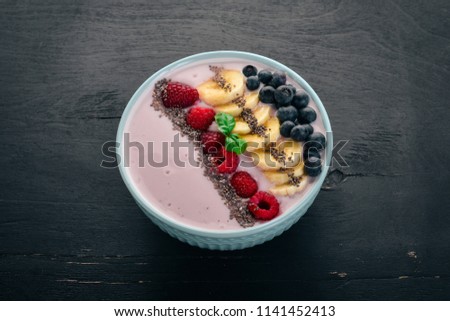 Yogurt with blueberries, raspberries and banana. In the plate. On a wooden background. Top view. Free space for text.