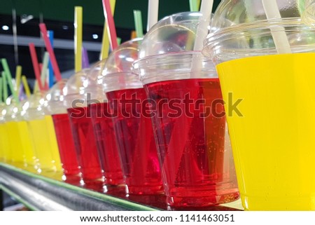 Colorful refreshment drinks lemonade in plastic glasses, in stand with takeaway food
