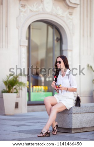 Young woman with street food with beautiful horses in the carriage background. Beautiful girl with fruits outdoors