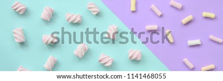 Colorful marshmallow laid out on violet and blue paper background. pastel creative textured pattern. minimal