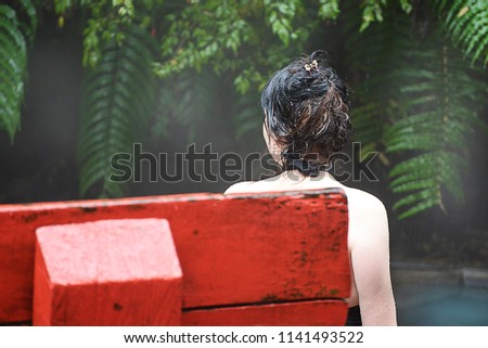 Girl enjoys bathing and a spa in a hot swimming pool in a natural resort, surrounded by a dense forest or jungle. Thermal volcanic springs  Termas Geometricas, Chile, South America.