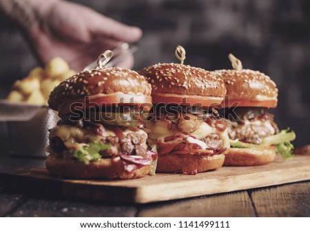 Homemade delicious juicy burger with beef, cheese, tomato and caramelized onion and potato balls. Rustic style. VIntage toned image.