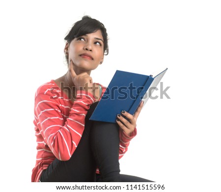 Pretty young girl holding book and posing on white background
