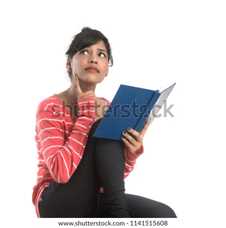 Pretty young girl holding book and posing on white background
