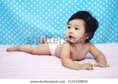 Portrait of pretty baby girl asian smiling to lie leisurely on the bed.