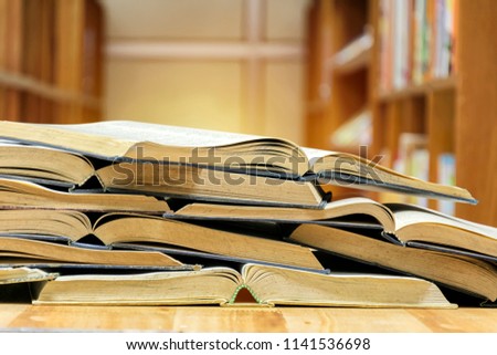 Many books are opened overlapping. Put on the table in the library. It is a place to collect knowledge.