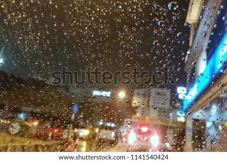 Blured background with rains drop on glass and cars on the road.- soft focus