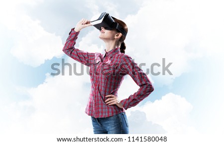 Young caucasian woman in virtual reality helmet against sky background