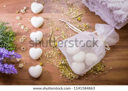 Soap in the shape of heart with flowers and white towel at wooden background