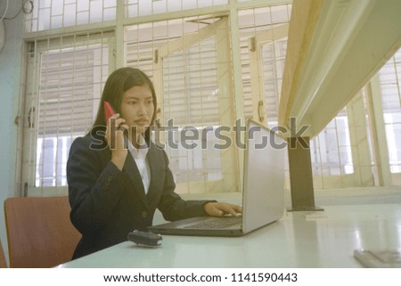 Beautiful Asian business woman working on a computer and a phone in office