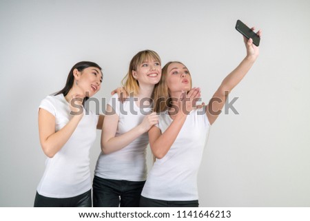 Beautiful funny girls make selfie. Girls in white T-shirts.
