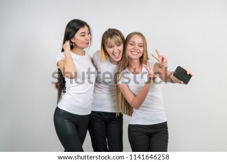 Beautiful funny girls make selfie. Girls in white T-shirts.