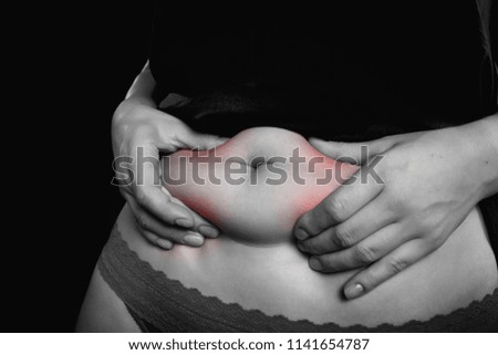 Fat woman belly. Woman checks and pinching excess fat on her paunch. Black & white picture- isolated on black background.