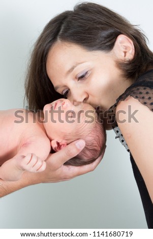 Young cute mother kissing her little newborn baby boy