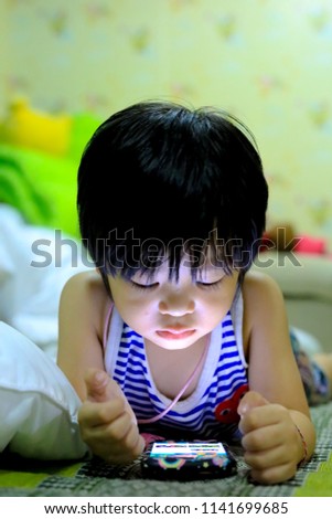 cute Asia kid playing games on smartphone