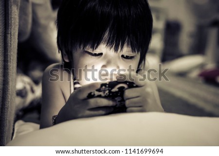 Cute Asia kid playing games on smartphone