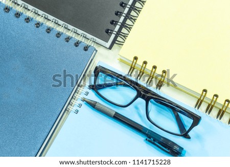 Close up pen eyeglasses and spiral notebook, Pattern background