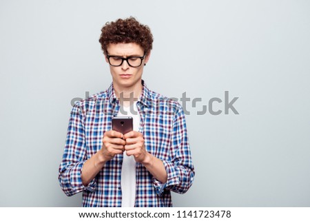 Young attractive handsome guy wearing casual checkered shirt typing message in smartphone. Copy blank empty space. Isolated over grey background