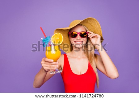 Party mood and beach style isolated on bright purple background! Blonde girl in red swimsuit laughs and offers summer cocktail for you