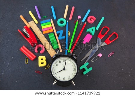 Back to school Accessories for school on a dark background Pencils Plasticine letters Letters Alarm clock Briefcase Chalk Top view