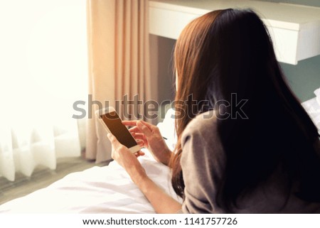 woman hold blank screen smartphone on bed with space, Toned image, Technology concept.