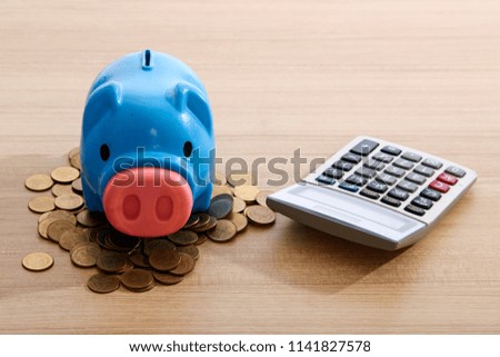 Plastic blue piggy bank with coins on wooden table