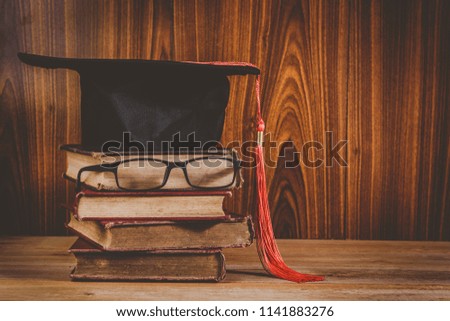 education and graduation concept, pile of old books wearing graduate cap and glasses, vintage tone
