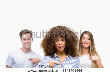 Group of young people over white background with surprise face pointing finger to himself