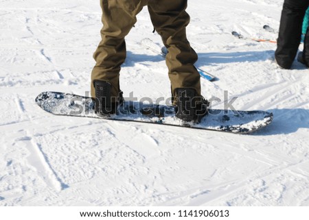 Snowboarding legs on winter mountain top. Snowboarder is riding from snow hill
