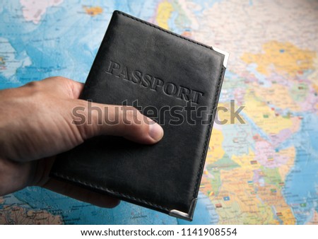 passport of a citizen in the hand of a person on the background of a map of the world