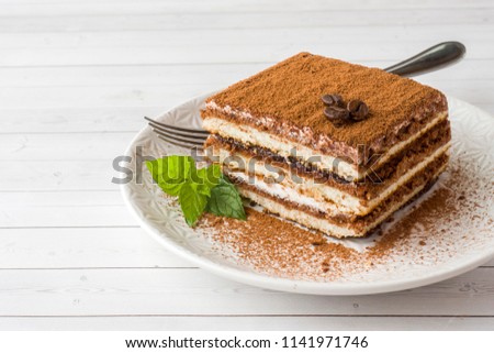 Delicious Tiramisu cake with coffee beans and fresh mint on a plate on a light background. Royalty-Free Stock Photo #1141971746