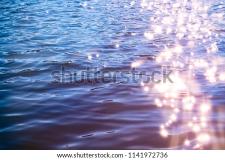 Sunlight twinkling off river water with small waves. Calm summer evening. Colorful background Royalty-Free Stock Photo #1141972736