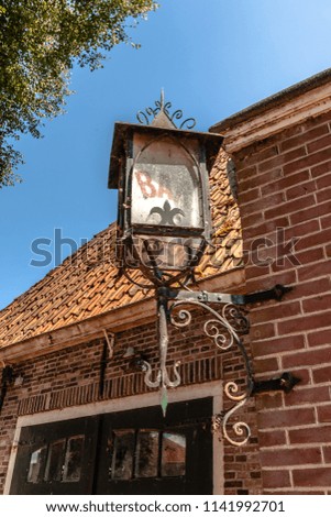 Ornate iron lamp made of wrought iron by a traditional blacksmith. Typical black painted vintage lantern with bar logo