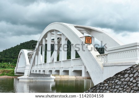 Vintage white railway bridge in Tha Chompoo , Mae Tha district, Lamphun, Thailand. The orange color sign written in Thai language dating the construction year in 1939 or 2482 B.E.