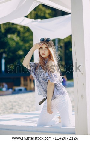 beautiful young long-haired girl in the summer park posing for pictures in a cabana