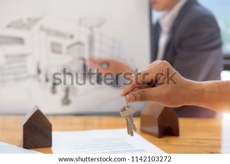 real estate agent holding house key to his client after signing contract,concept for real estate, moving home or renting property
