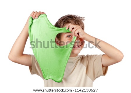 Cheerful boy holding a green slime and looking through its hole. Studio isolated on white background. Royalty-Free Stock Photo #1142130629