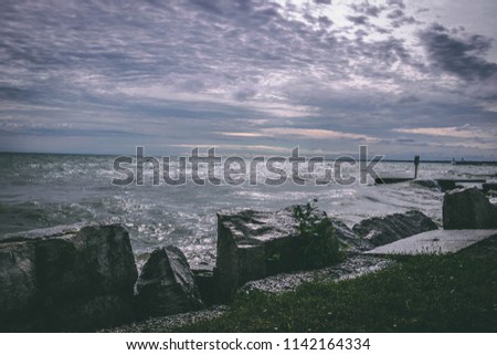Stunning sunset over water from the rocky shore; Beautiful sky over Lake Erie on a summer night; Point Pelee, Ontario, Canada 