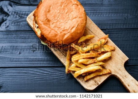  Burger and french fries on wooden table isolated on dark background.