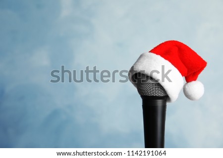 Microphone with Santa hat on color background. Christmas music concept Royalty-Free Stock Photo #1142191064