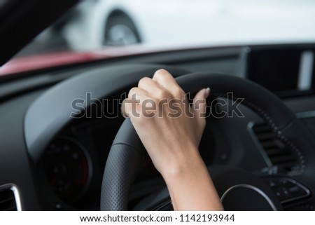 The hand of a girl with a stylish manicure lies on the handlebars in a saloon car. Close-up