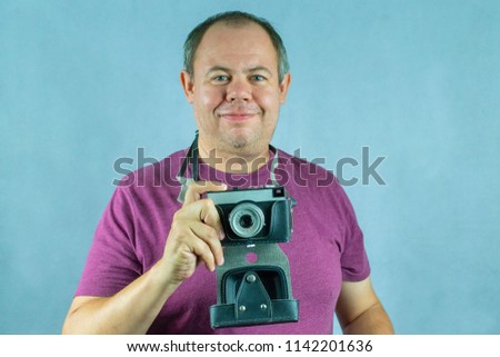 a man with an old film camera in his hand makes a photo with a smile