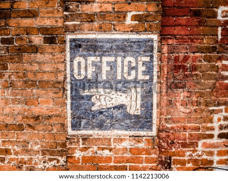 Hand painted office signe flaking away from a brick wall