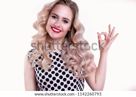 Young blond woman showing gesture - OK. Happy woman with blue eyes smiling on isolated white background