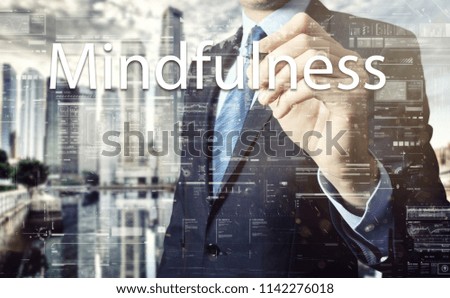 businessman writes a popular buzzword on a virtual whiteboard: Mindfulness
