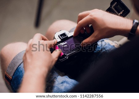 man installing photo film cartridge in film camera