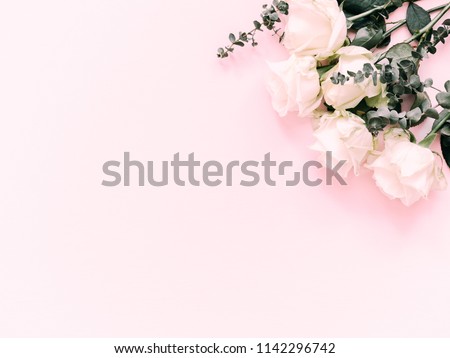 Flowers composition. Border made of white rose flowers and eucalyptus branches on a pink background. Flat lay, top view, copy space