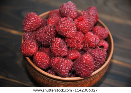 beautiful clay dish with raspberries on a napkin, on a wooden table. View from above. Royalty-Free Stock Photo #1142306327