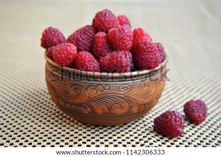 beautiful clay dish with raspberries on a napkin. Side view. Royalty-Free Stock Photo #1142306333